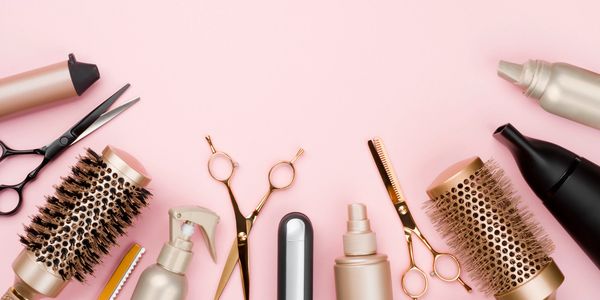 Professional hair styling tools arranged on pink background