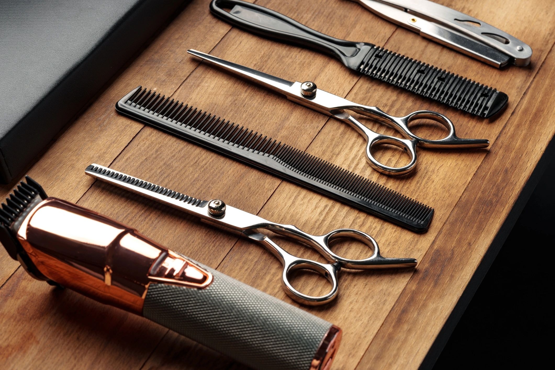 Professional salon scissors and clippers on wooden surface